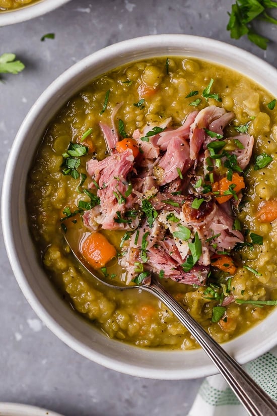 A white bowl filled with split pea soup with ham.