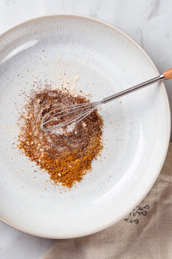 This crispy roasted chickpeas recipe is perfectly spiced, with lots of crunch! It's an easy snack that's packed with protein and fiber. Overhead view of whisk mixing spices for chickpeas