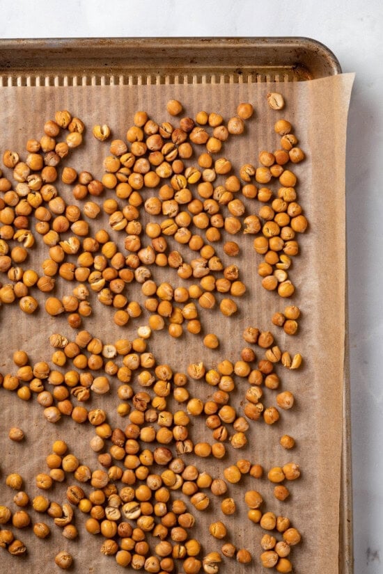 This crispy roasted chickpeas recipe is perfectly spiced, with lots of crunch! It's an easy snack that's packed with protein and fiber. Overhead view of roasted chickpeas on sheet pan