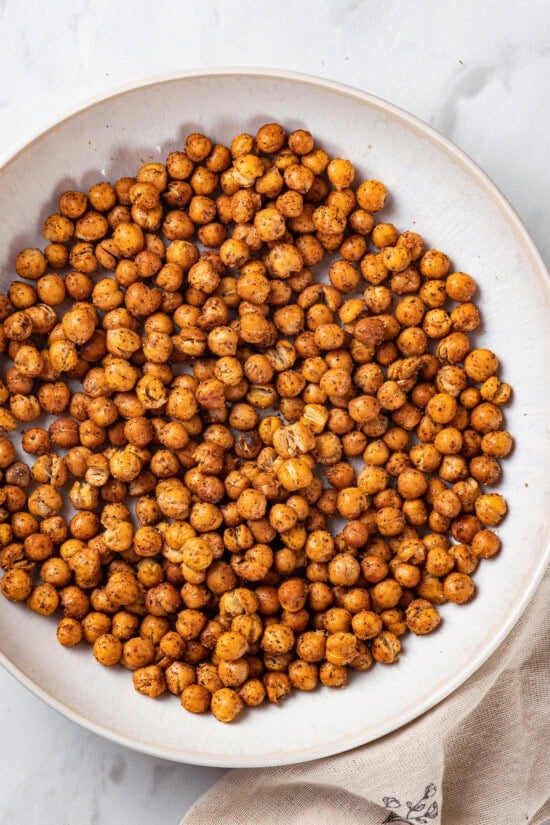This crispy roasted chickpeas recipe is perfectly spiced, with lots of crunch! It's an easy snack that's packed with protein and fiber. Overhead view of crispy oven-roasted chickpeas in bowl