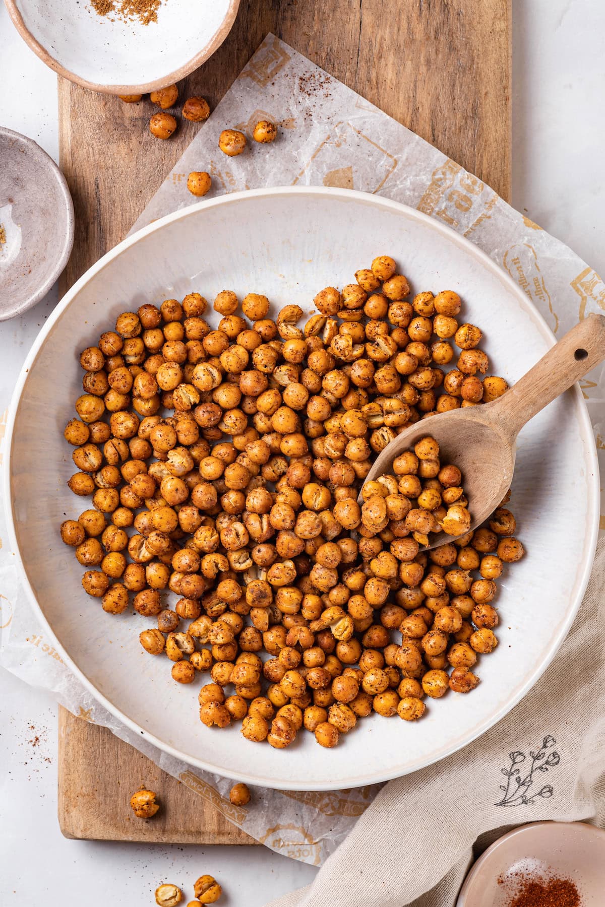 This crispy roasted chickpeas recipe is perfectly spiced, with lots of crunch! It's an easy snack that's packed with protein and fiber. Overhead view of crispy roasted chickpeas in bowl with wooden scoop