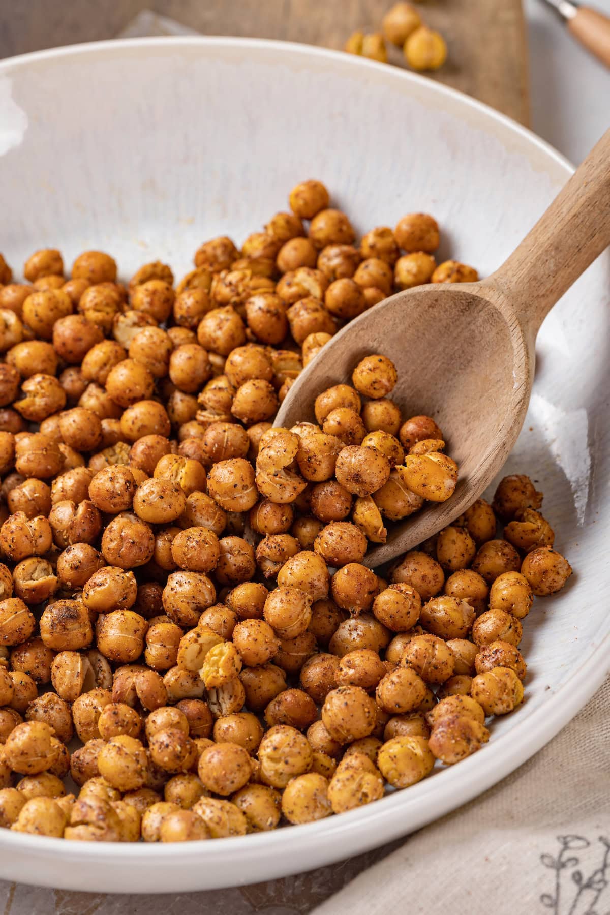 This crispy roasted chickpeas recipe is perfectly spiced, with lots of crunch! It's an easy snack that's packed with protein and fiber. Scooping roasted chickpeas from bowl