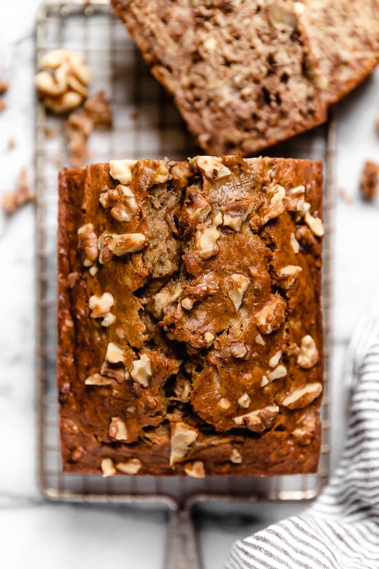 This delicious banana bread is be made with ripe mashed bananas, nuts, and spices. It's made healthier with less butter, oil and sugar. A loaf of banana nut bread sliced in half.