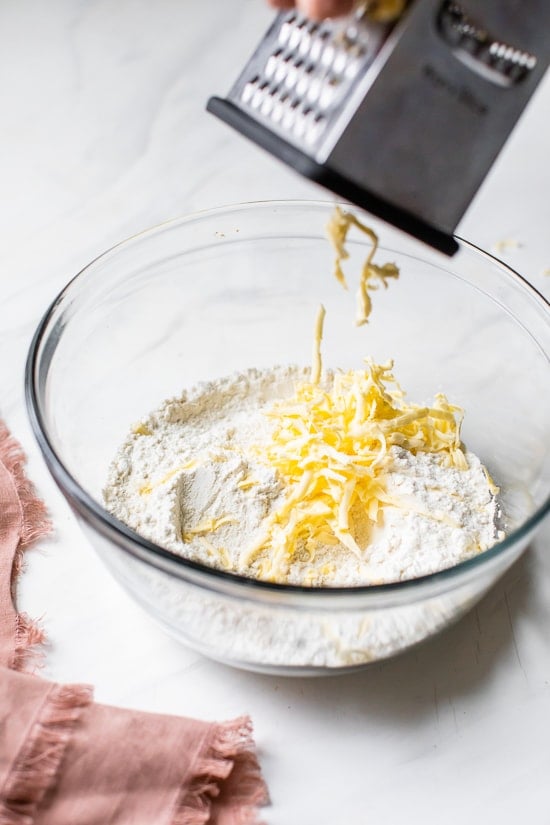 Grating butter into dry ingredients to make scone batter.