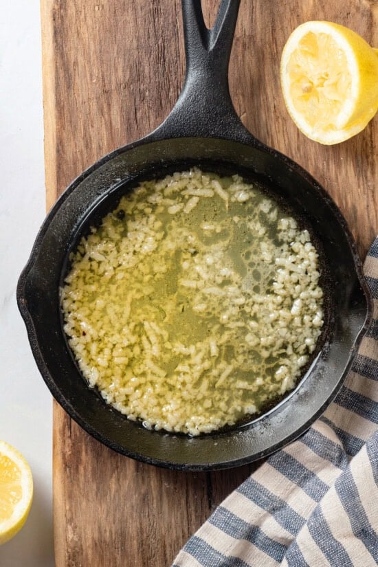 This simple baked tilapia recipe is finished with a garlicky lemon butter sauce and parsley, making it a delicious and light weeknight dinner! Garlic butter lemon sauce in skillet