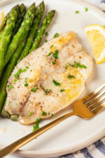 Closeup of baked tilapia on plate with asparagus