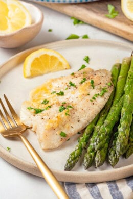Healthy baked tilapia on plate with asparagus spears