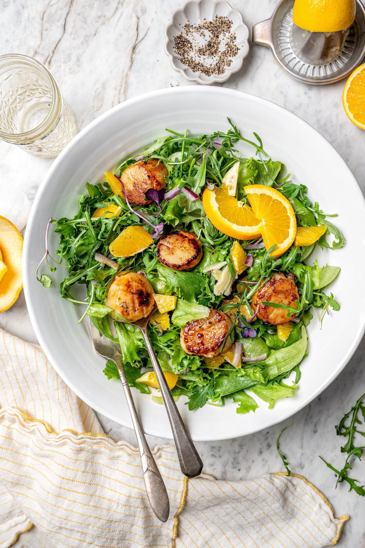 Pan seared scallops taste like a special occasion dinner but they’re easy enough for a weeknight. Serve over salad for a light, healthy meal! Pan seared scallops in serving bowl with citrus salad