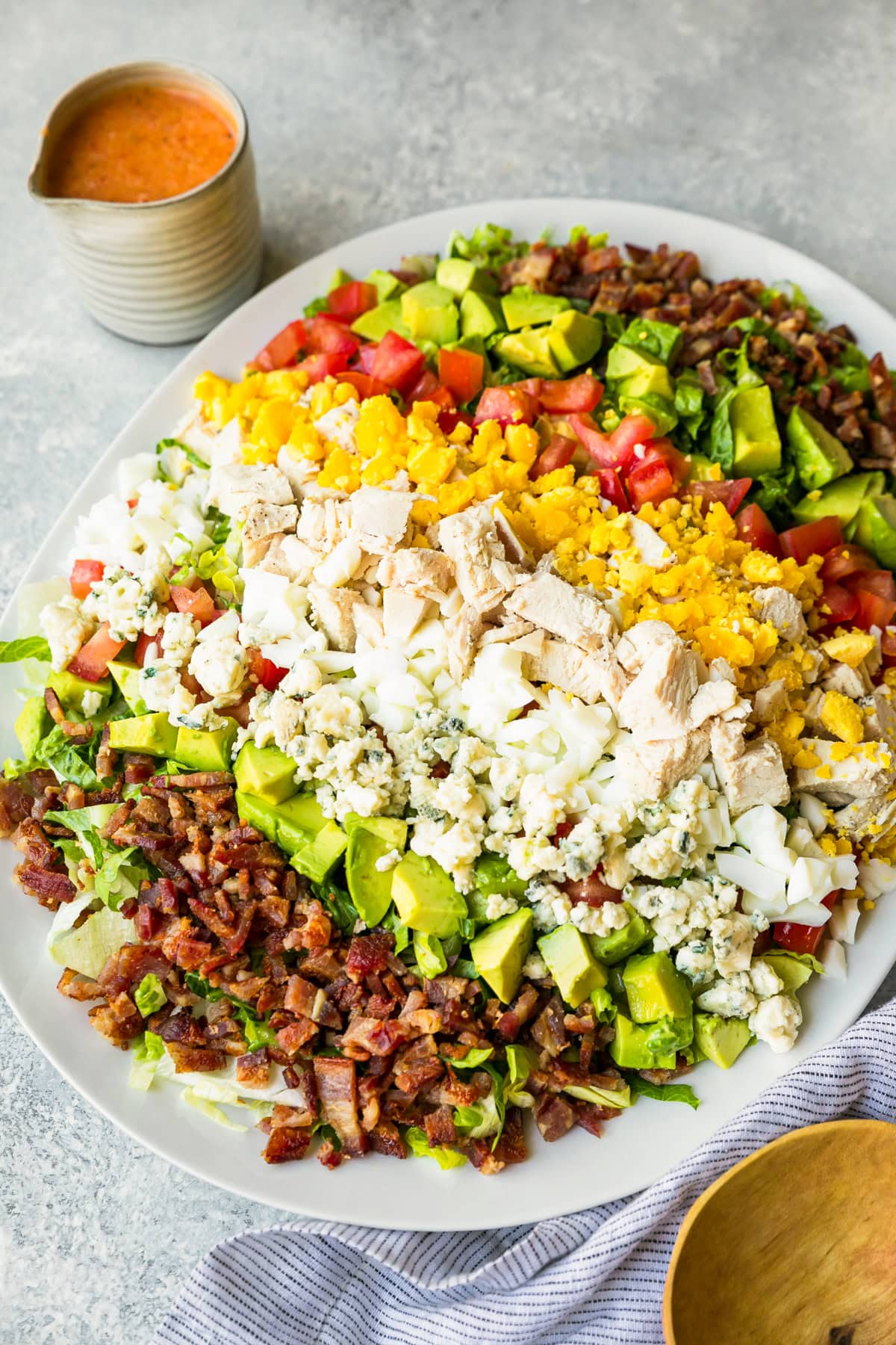 Layers of hard boiled eggs, bacon, blue cheese, tomatoes and avocado make up this classic Cobb salad recipe. It's the perfect lunch salad! Classic Cobb salad on platter