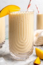 3 homemade mango lassis in glasses with mango slices on rim for garnish