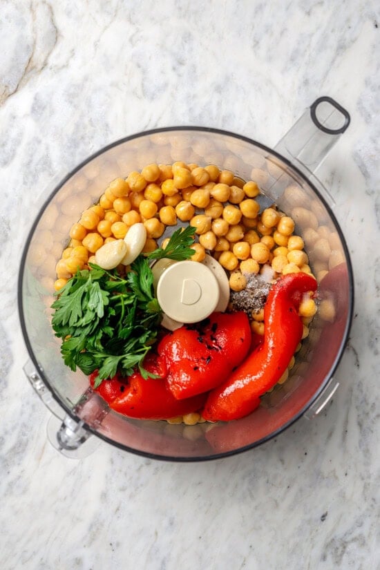 Smoky bell peppers add so much flavor to this roasted red pepper hummus recipe! Pair it with your favorite veggies for a healthy snack. Overhead view of ingredients for roasted red hell pepper hummus in food processor
