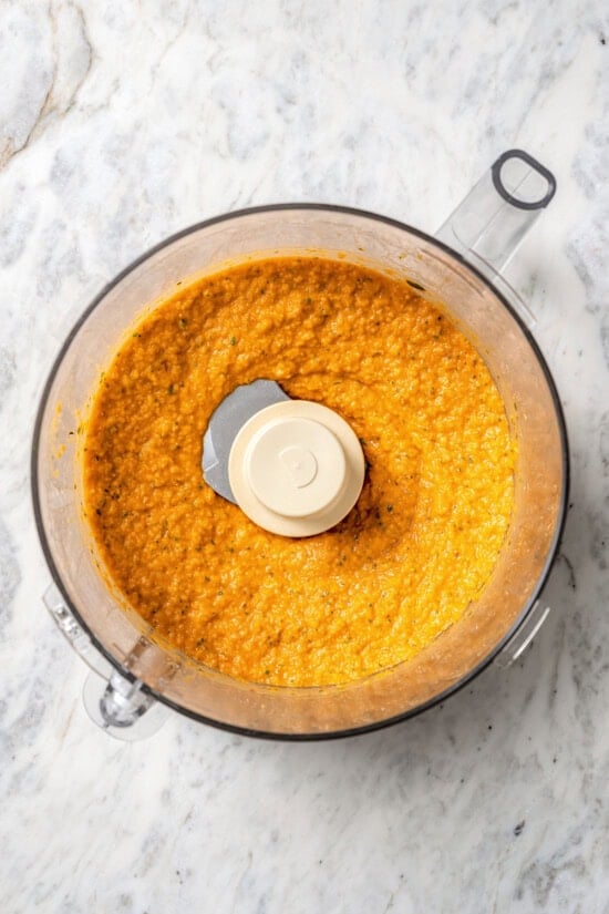 Smoky bell peppers add so much flavor to this roasted red pepper hummus recipe! Pair it with your favorite veggies for a healthy snack. Overhead view of roasted red pepper hummus in food processor