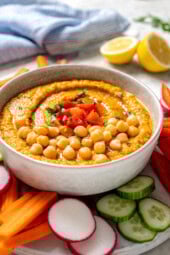 Bowl of roasted red bell pepper hummus garnished with peppers and chickpeas