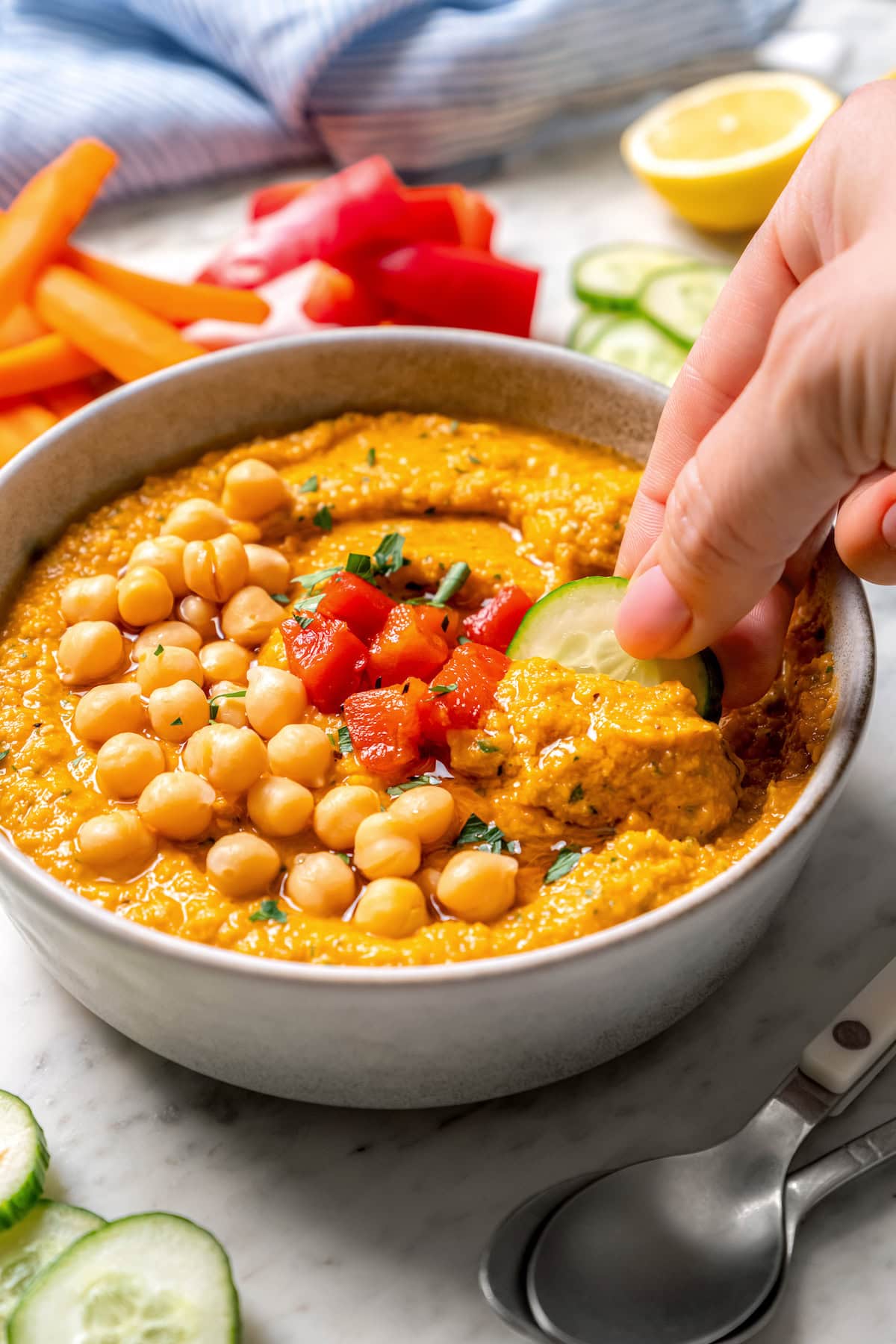 Smoky bell peppers add so much flavor to this roasted red pepper hummus recipe! Pair it with your favorite veggies for a healthy snack. Dipping cucumber into roasted red pepper hummus