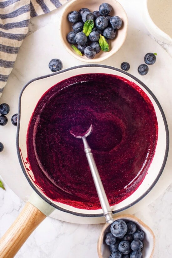 This easy blueberry compote recipe is a 3-ingredient fruit topping perfect for serving over ice cream, yogurt, and more. So summery! Overhead view of blueberry compote in saucepan