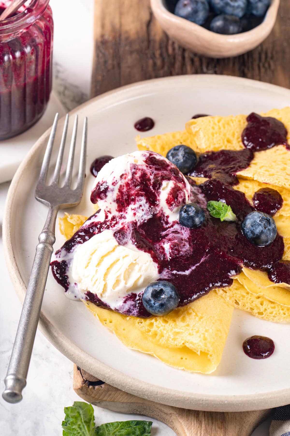 This easy blueberry compote recipe is a 3-ingredient fruit topping perfect for serving over ice cream, yogurt, and more. So summery! Plate of crepes with ice cream and blueberry compote