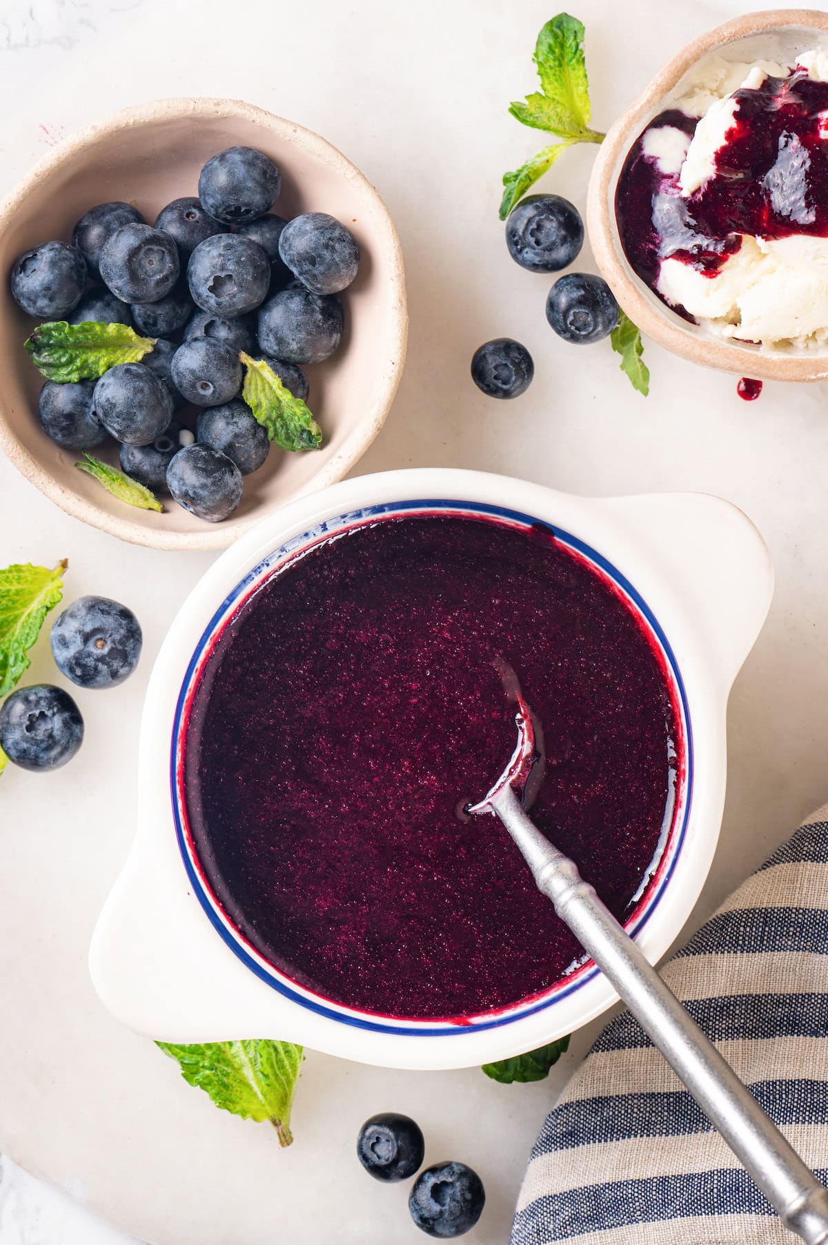 This easy blueberry compote recipe is a 3-ingredient fruit topping perfect for serving over ice cream, yogurt, and more. So summery! Overhead view of blueberry compote in bowl with spoon