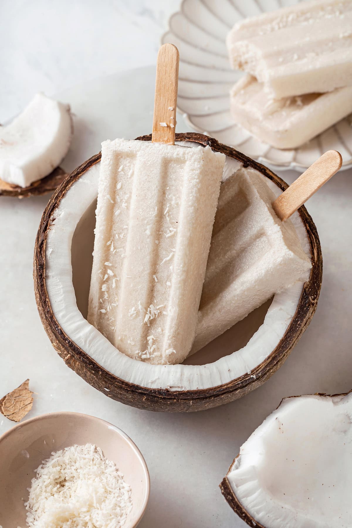 Two coconut popsicles set in halved coconut
