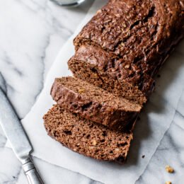 Sliced Chocolate Zucchini Bread loaf on white marble