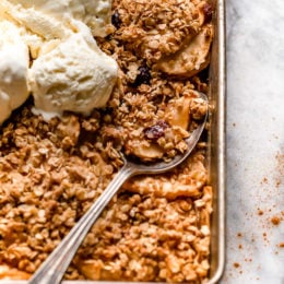 Golden brown apple crisp baked with oat topping and vanilla ice cream on top