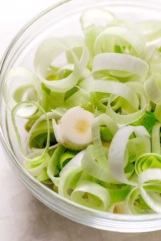 Cozy and comforting, this Potato Leek Soup is an easy soup recipe the whole family will love. It's rich and creamy, without any heavy cream! Sliced leeks in bowl