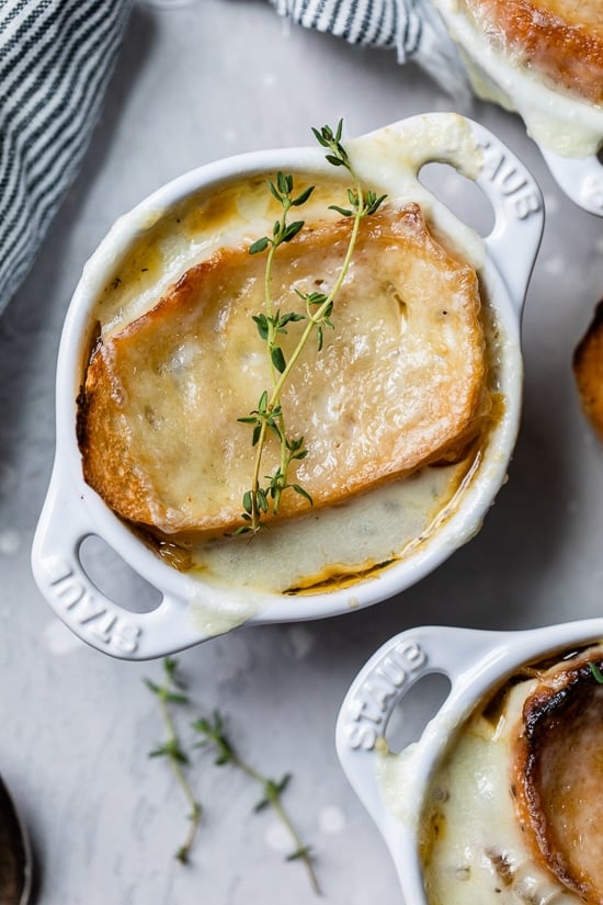 This lightened-up French onion soup recipe is just as delicious as the original, with beefy broth, caramelized onions, and melty cheese! Overhead view of French onion soup in ramekins.