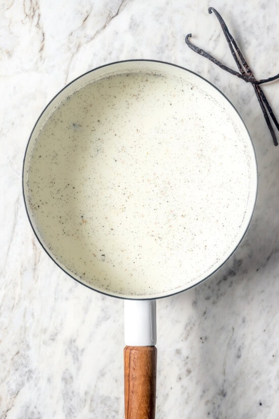 This easy lightened up homemade eggnog recipe comes together quickly and it’s so much tastier than store-bought. Creamy and delicious! Milk and vanilla beans in pan