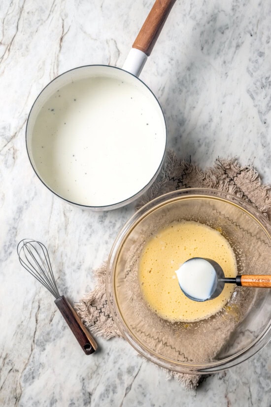 This easy lightened up homemade eggnog recipe comes together quickly and it’s so much tastier than store-bought. Creamy and delicious! Overhead view of warm milk in pan and egg mixture in bowl