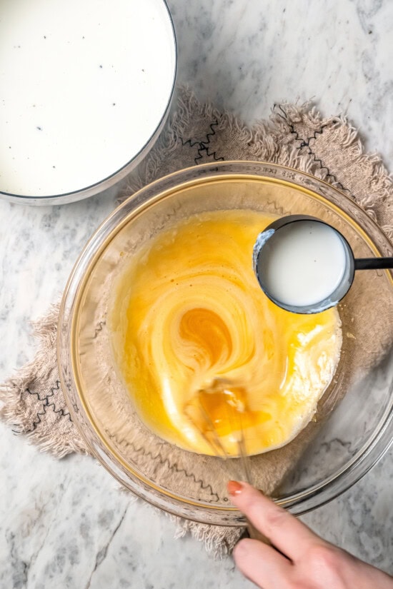 This easy lightened up homemade eggnog recipe comes together quickly and it’s so much tastier than store-bought. Creamy and delicious! Tempering eggs in glass bowl