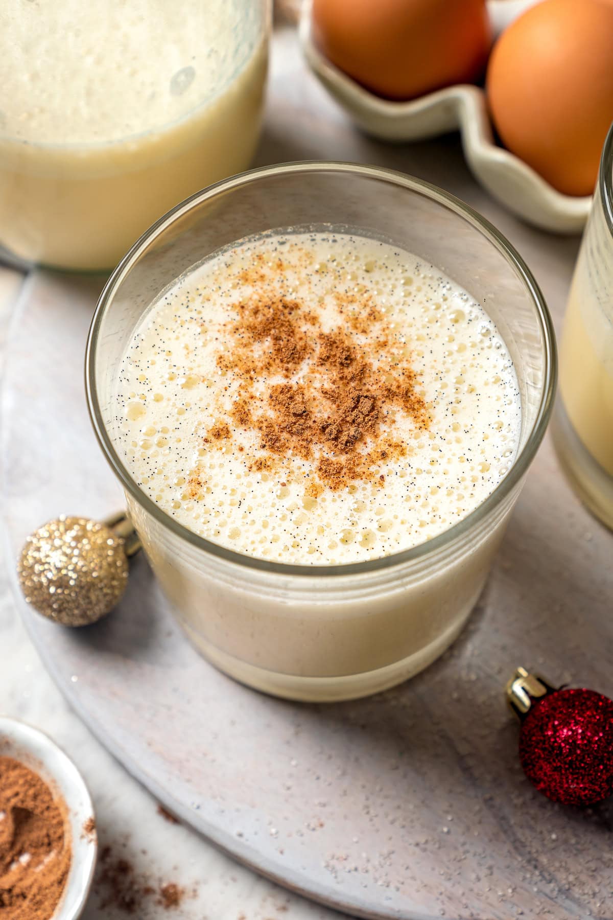 This easy lightened up homemade eggnog recipe comes together quickly and it’s so much tastier than store-bought. Creamy and delicious! Top-down view of eggnog in glass with grated nutmeg on top
