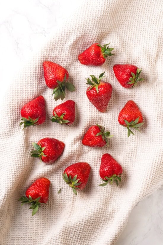 Chocolate-covered strawberries are an elegant treat that's incredibly easy to make at home. You'll never buy them at the store again! Strawberries drying on white kitchen towel