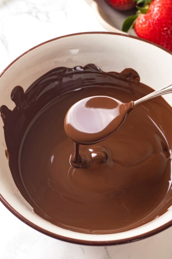 Chocolate-covered strawberries are an elegant treat that's incredibly easy to make at home. You'll never buy them at the store again! Spoon dripping melted chocolate into bowl