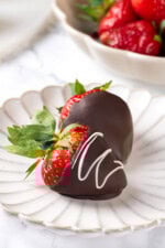 Two chocolate-covered strawberries on white plate