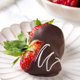 Two chocolate-covered strawberries on white plate