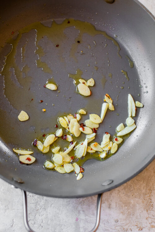 In a large skillet, heat oil on medium heat and add the garlic and red pepper flakes.