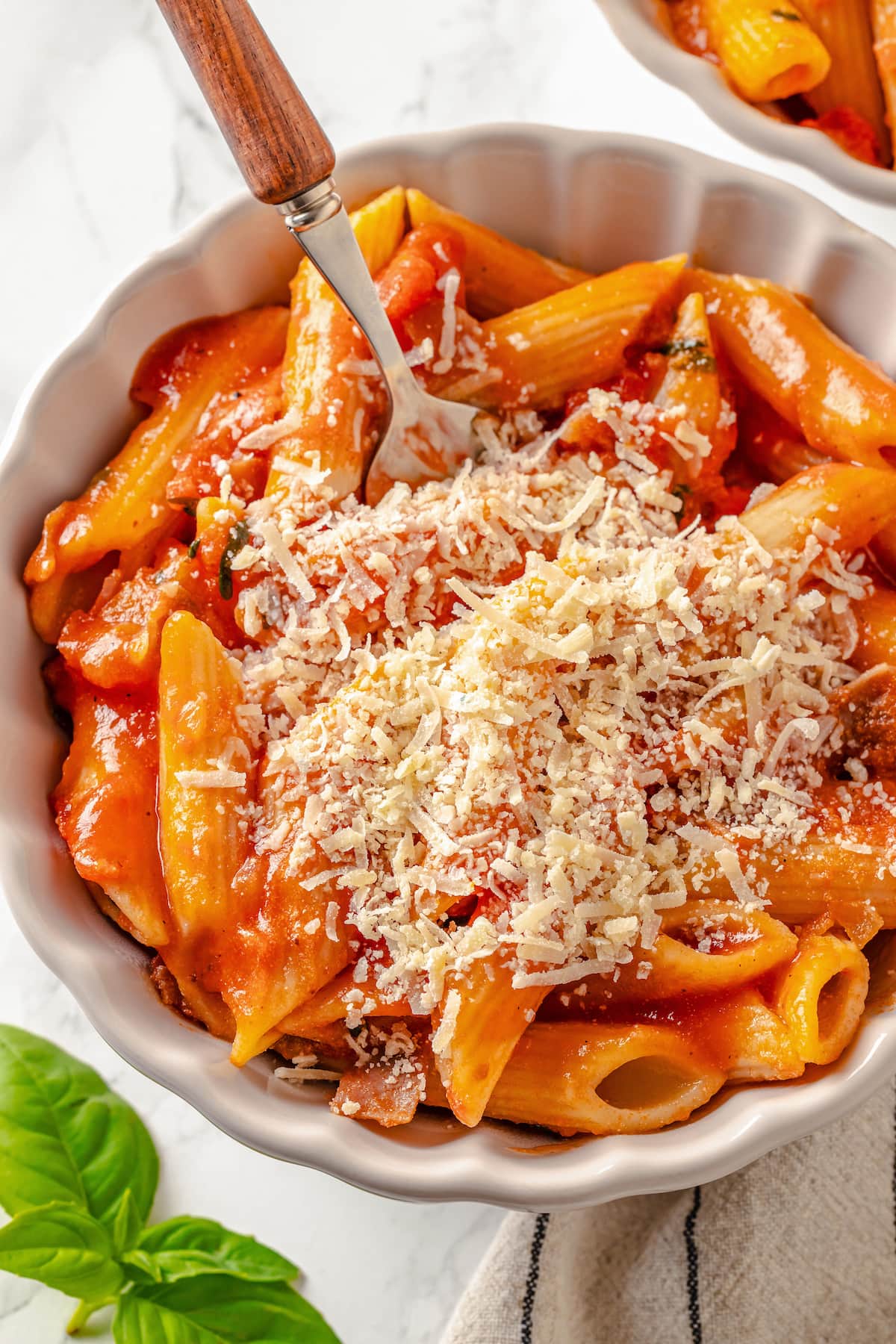 Penne alla Vodka is a simple yet showstopping pasta dish. The creamy tomato vodka sauce comes together in less than 30 minutes. A bowl of penne alla vodka topped with grated cheese