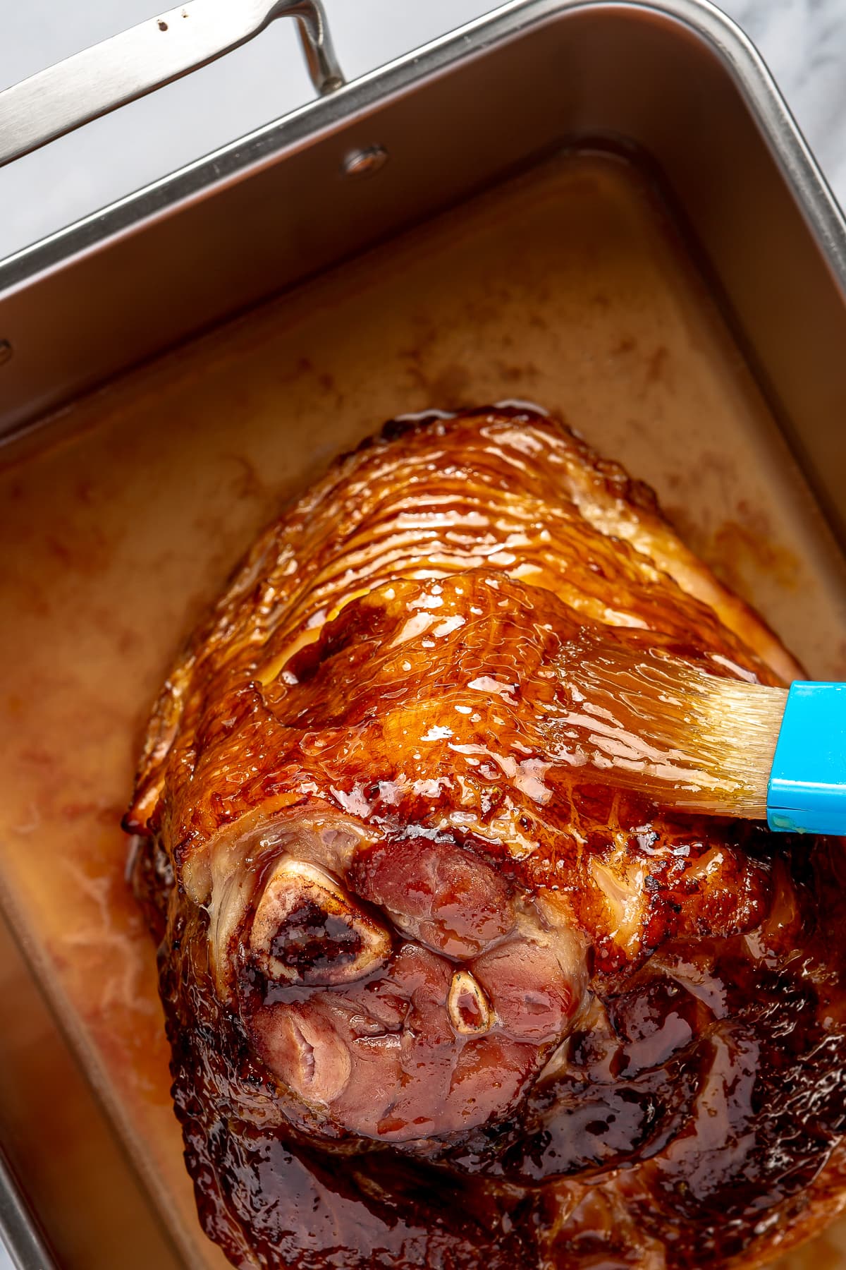 brushing honey glaze on ham