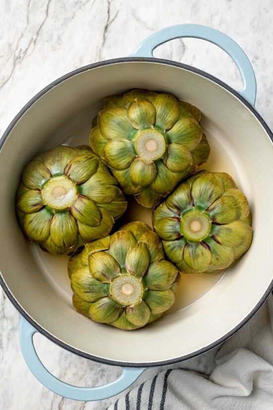 Stuffed artichokes are a classic Italian dish made with crispy, cheesy breadcrumbs. My version is a bit lighter but just as delicious! Overhead view of boiled artichokes in pot