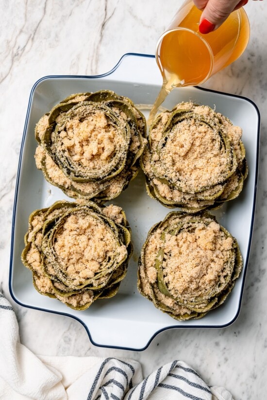 Stuffed artichokes are a classic Italian dish made with crispy, cheesy breadcrumbs. My version is a bit lighter but just as delicious! Overhead view of stuffed artichokes in baking dish before baking