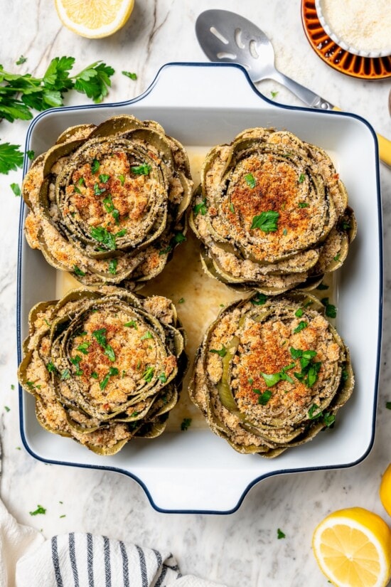 Stuffed artichokes are a classic Italian dish made with crispy, cheesy breadcrumbs. My version is a bit lighter but just as delicious! Overhead view of stuffed artichokes in baking dish