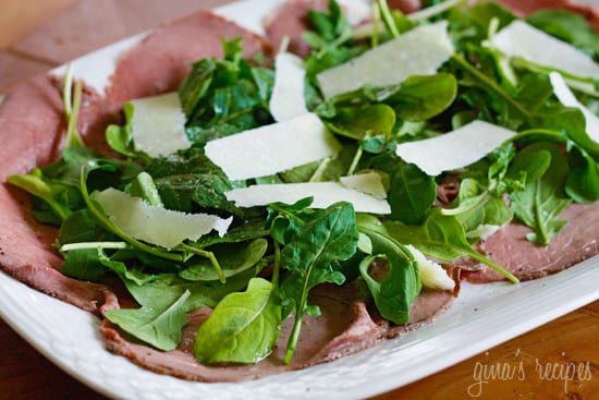 A platter with thin sliced roast beef, arugula and shaved asiago