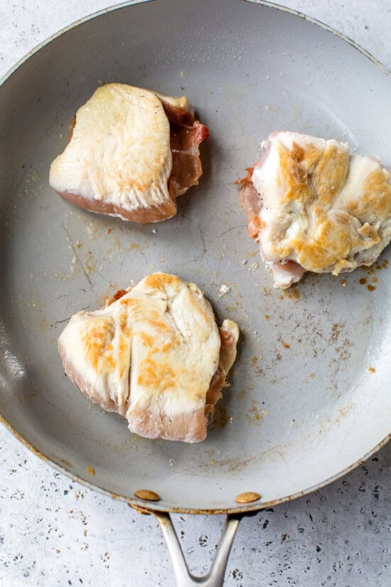 This lighter chicken saltimbocca is a restaurant-quality dinner with chicken cutlets stuffed with prosciutto and sage in white wine sauce. Chicken saltimbocca cooking in skillet