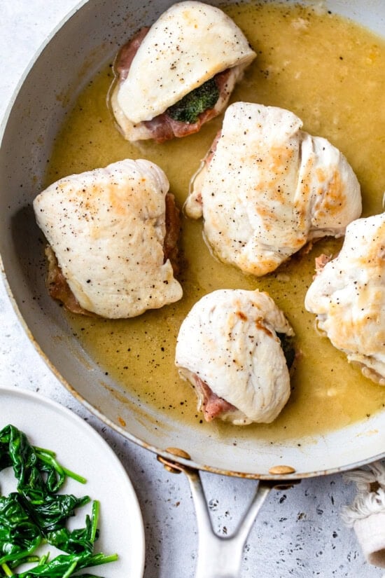 This lighter chicken saltimbocca is a restaurant-quality dinner with chicken cutlets stuffed with prosciutto and sage in white wine sauce. Chicken saltimbocca cooking in skillet with white wine sauce