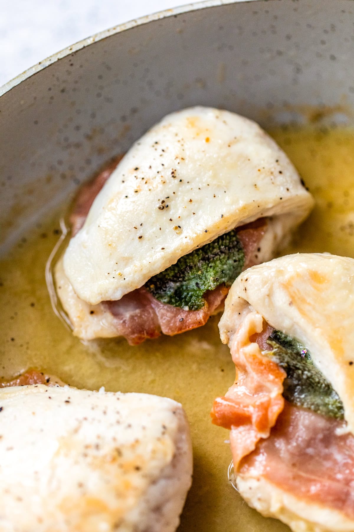 This lighter chicken saltimbocca is a restaurant-quality dinner with chicken cutlets stuffed with prosciutto and sage in white wine sauce. Lightened up chicken saltimbocca cooking in skillet