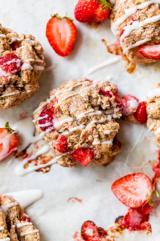 Strawberry Scones drizzled with icing on parchment paper.