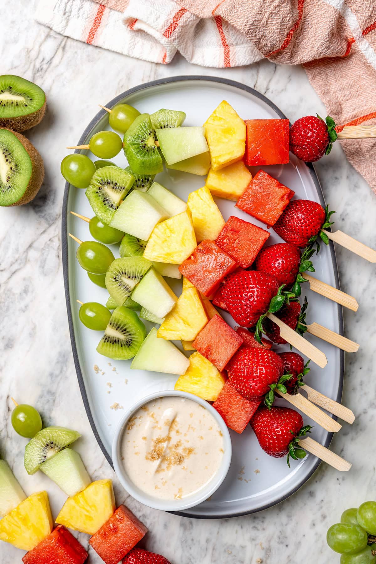 Rainbow fruit kabobs on platter with dip