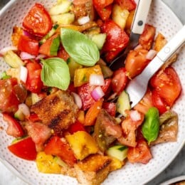 Overhead view of panzanella salad in bowl with fork and spoon