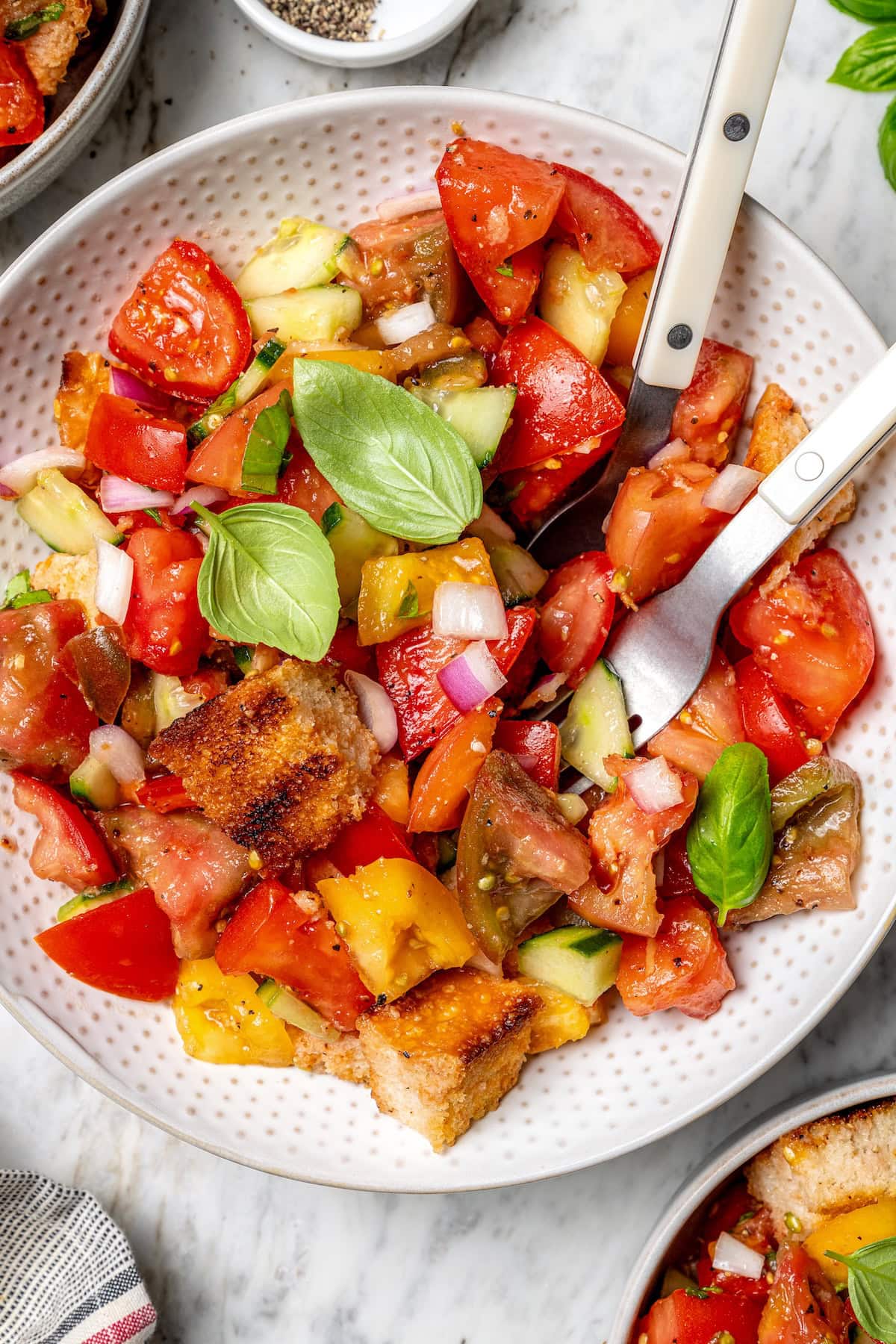 Overhead view of panzanella salad in bowl with fork and spoon