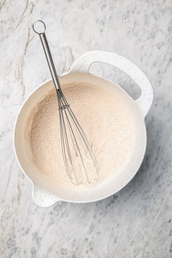 This lightened up version of pumpkin pancakes is also extra fluffy! You'll love the cozy fall flavor in this easy, healthier pancake recipe. Overhead view of dry ingredients for pancakes in bowl with whisk