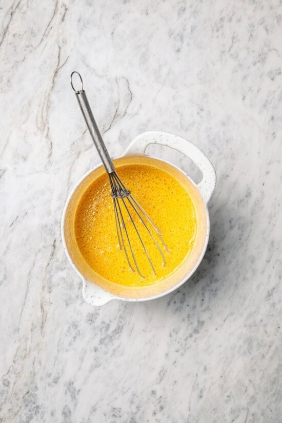 This lightened up version of pumpkin pancakes is also extra fluffy! You'll love the cozy fall flavor in this easy, healthier pancake recipe. Overhead view of wet ingredients in mixing bowl with whisk